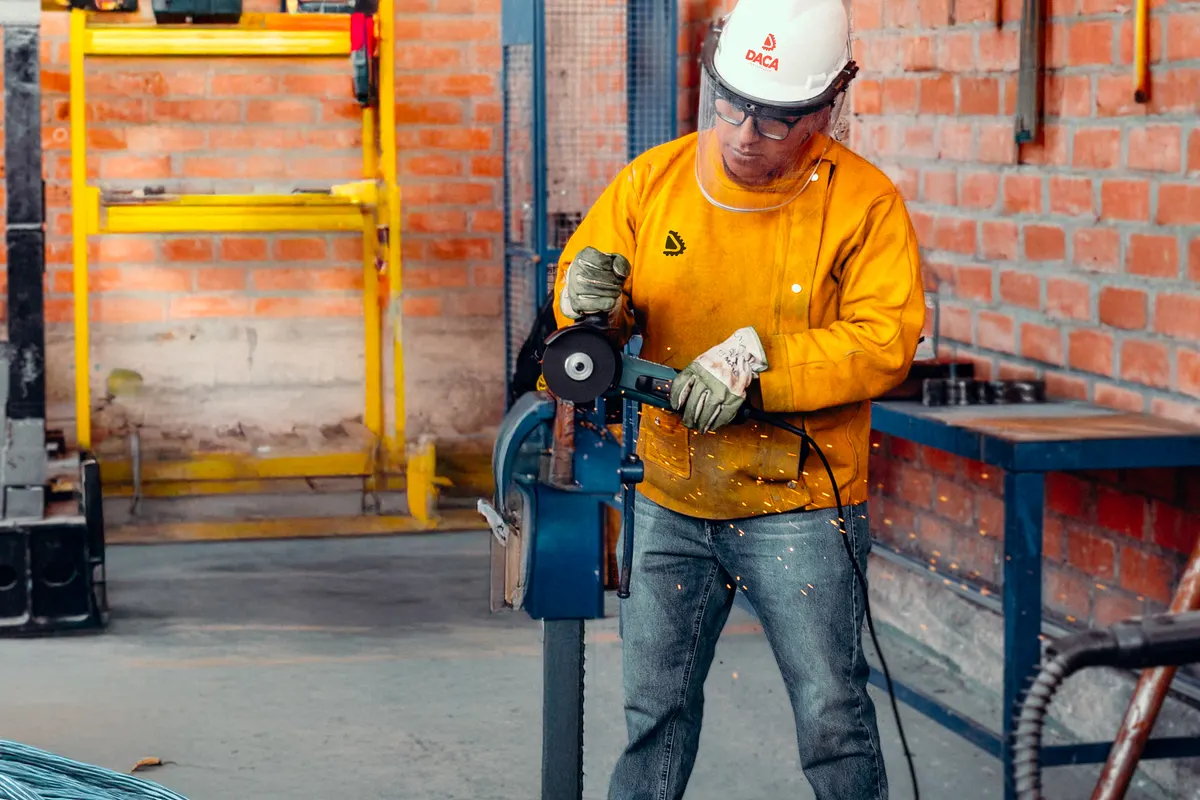 Operario usando una amoladora en un taller metalmecánico
